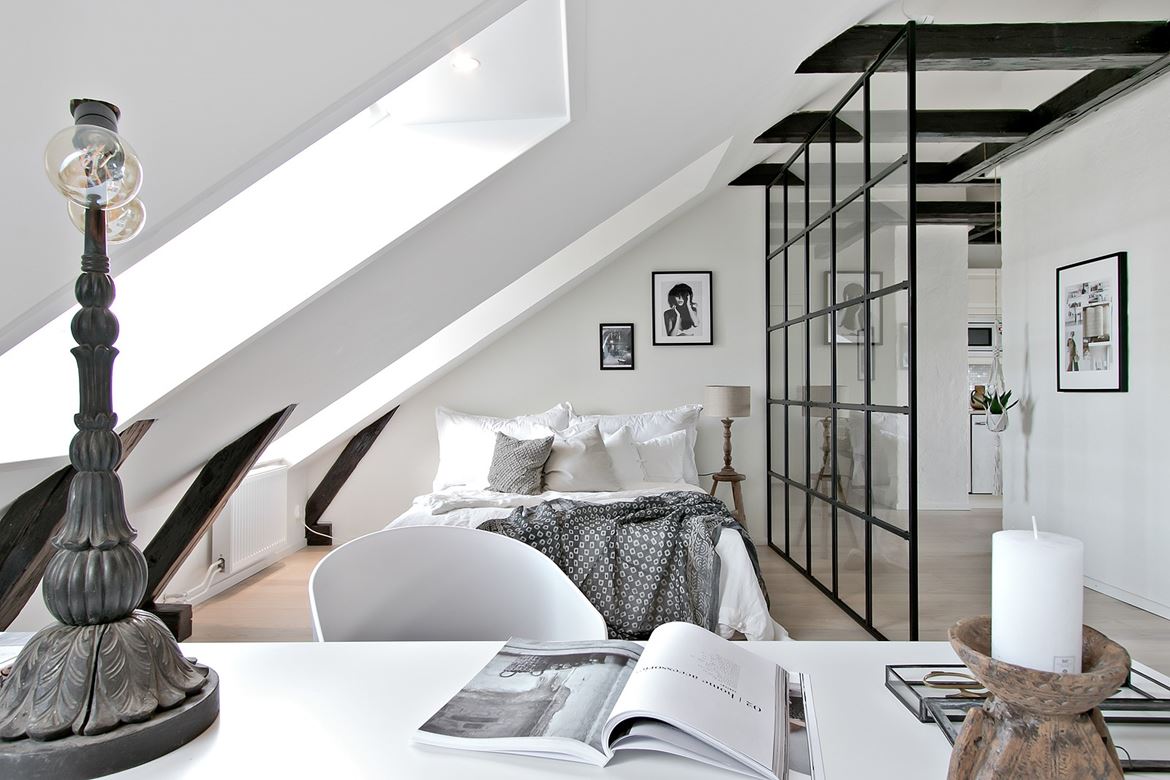 Sypialnia na poddaszu z drewnianymi belkami stropowymi